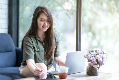 Young woman using mobile phone while sitting at home