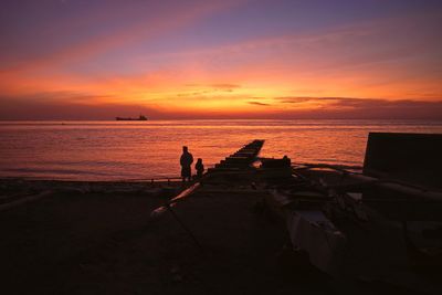 Silhouette people on beach against sky during sunset