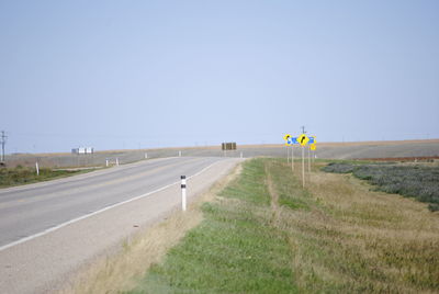 Road sign on field against clear sky