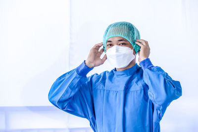 Portrait of doctor wearing mask against white background