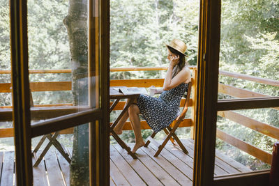 Woman drinking coffee and reading newspapers on balcony