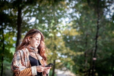 Young woman looking away while standing on tree