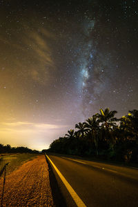 Road amidst trees against sky at night