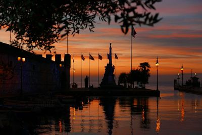 Silhouette trees by lake against sky during sunset