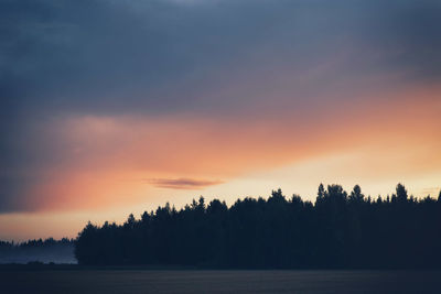 Silhouette of trees on landscape at sunset