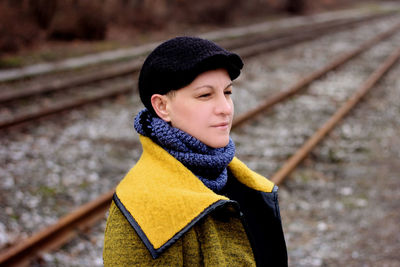 Woman looking away standing by railroad track during winter