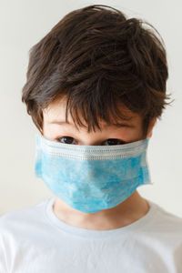 Portrait of boy in medical mask against white background