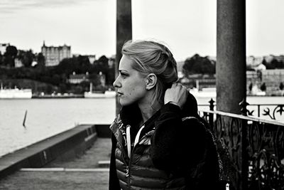 Thoughtful woman looking away at harbor against sky