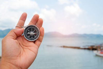 Person holding ring over sea against sky