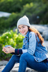 Portrait of smiling young woman using mobile phone outdoors