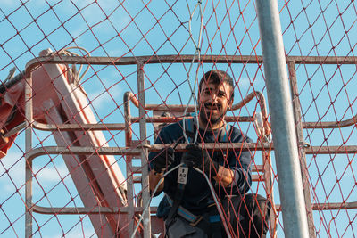 Portrait of young man against metal fence