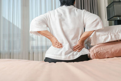 Rear view of man relaxing on bed at home