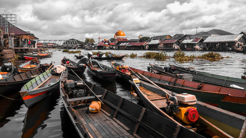 Boats moored at harbor against sky