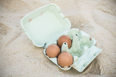 High angle view of eggs in carton at sandy beach