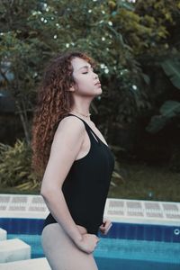 Young woman standing against waterfall