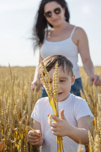 Happy family on a summer walk, mother and child walk in the wheat field and enjoy the beautiful nat
