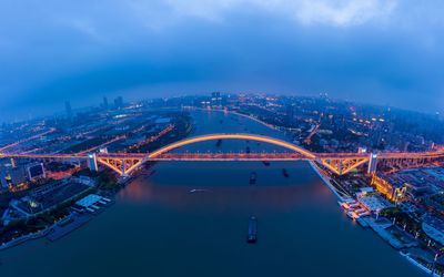 Aerial view of illuminated bridge over river at dusk