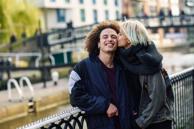 Woman kissing man on cheek in city