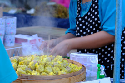 Midsection of woman holding food at market stall