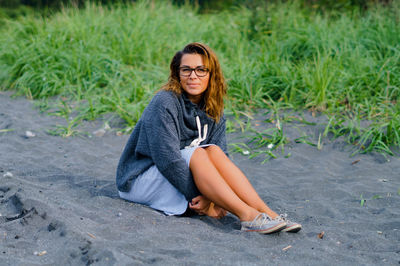 Full length portrait of mid adult woman sitting at beach