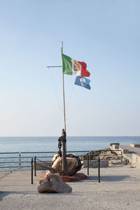 Flag on beach against clear sky