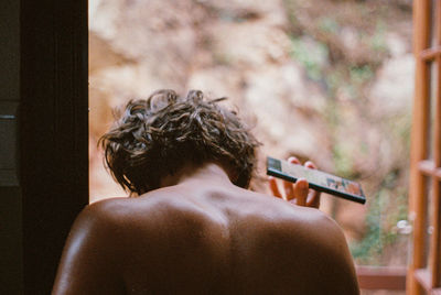 Rear view of shirtless man holding woman outdoors