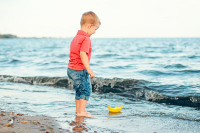 Full length of boy on beach against sky