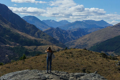 Rear view of woman standing on mountain against sky