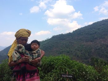 Mother and son standing on mountain against sky