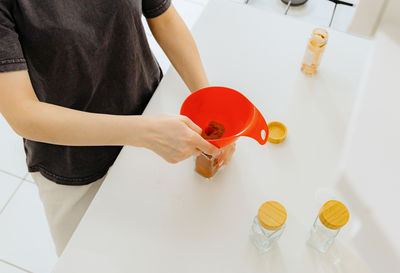 A girl pours spice seasoning from a bag into a jar.