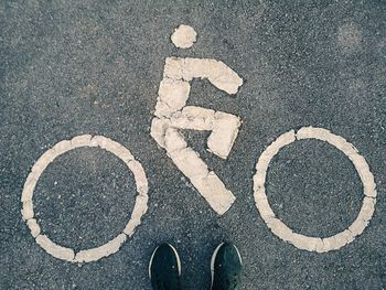 Low section of person standing by bicycle lane sign