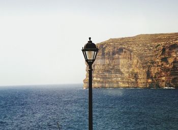 Street light by sea against clear sky