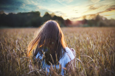 Rear view of woman walking on field against sky