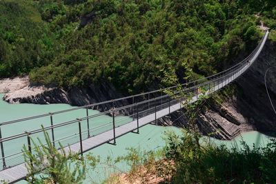 Bridge over a white blue river lake in the french alps with trees