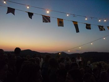 Illuminated lights against sky at sunset