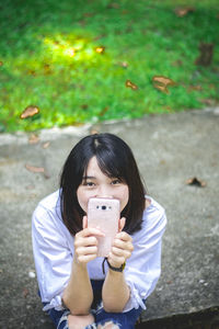 Portrait of teenage girl photographing outdoors