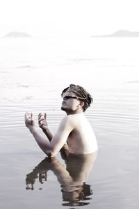 Shirtless man with leaf on face in lake