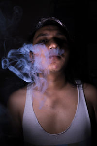 Portrait of man smoking against black background