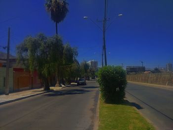 Road by trees against clear sky