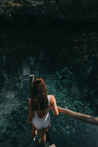 Rear view of woman standing by river