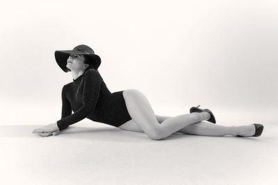 Side view of young woman sitting against white background