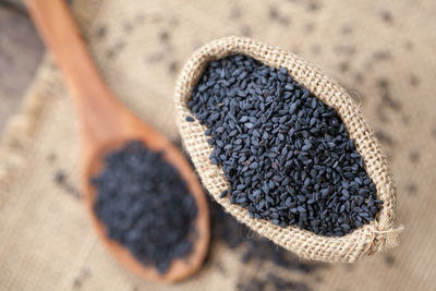 Close-up of black sesame seeds in wooden spoon and sack