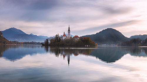 Reflection of trees in lake against cloudy sky
