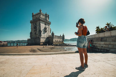 Full length of young woman standing against historic building