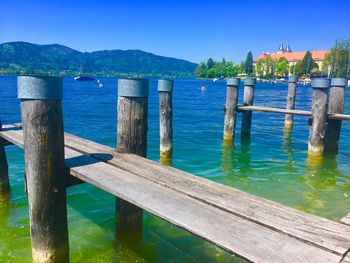 Wooden pier on lake against blue sky