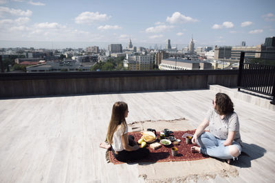 Woman with below-elbow amputation and girl having a healthy meal on the roof