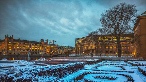 Snow covered buildings in city against sky