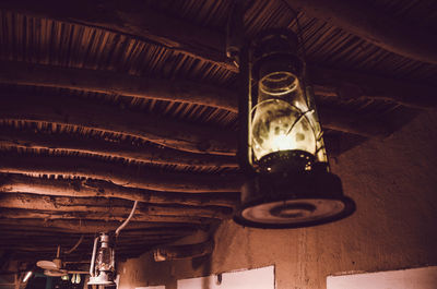 Low angle view of illuminated light bulb hanging from ceiling