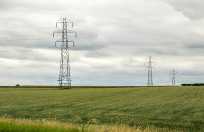 Electricity pylon on field against sky