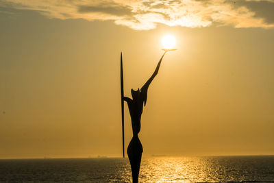 Silhouette woman at sea against sky during sunset